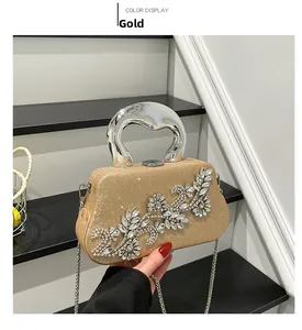 Detail of gold glitter evening bag with rhinestone flower and silver wavy handle