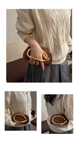 Détail d'une pochette en daim marron avec poignée dorée et ornements en strass brillants