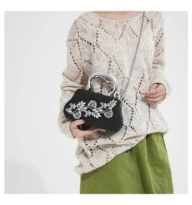 Detail of black shell evening bag with rhinestone flower and silver metal handle