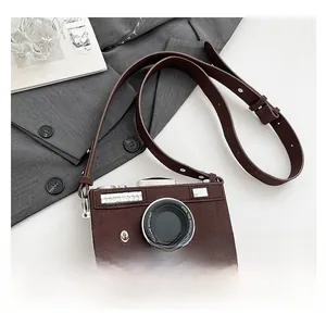 Détail du sac bandoulière vintage en forme d'appareil photo en daim marron sur blazer