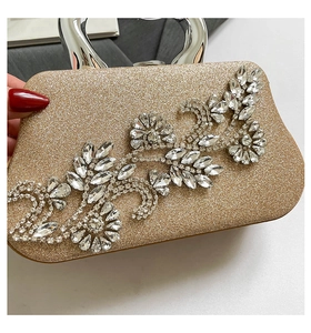 Detail of champagne gold evening clutch with rhinestone floral pattern and silver handle