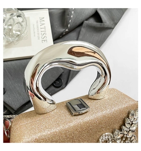 Detail of luxury gold glitter evening bag with silver fluid handle and rhinestone accents