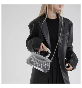 Détail d'une pochette argentée avec franges en cristal et bandoulière sur un mannequin