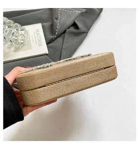 Close-up of golden glitter clutch featuring sparkling silver rhinestone flower clasp detail