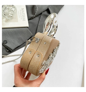 Detail of gold glitter evening bag featuring rabbit ear metal handles and crystal accents