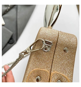 Detailed close-up of golden sequin texture and polished silver chain on a luxury evening bag