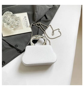 Close-up of white glitter dinner clutch with sculptural silver handle and metal chain