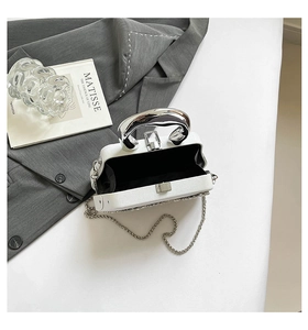 Detailed top view of white evening bag with silver metal handle and chain strap