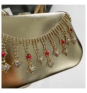 Détail d'une pochette dorée avec pampilles en strass et perles rouges élégantes