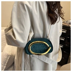 Sac bandoulière en velours vert foncé avec poignée dorée et chaîne sur un mannequin