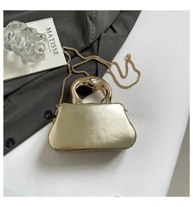 Détail d'un sac de soirée doré avec une poignée anneau unique et une fine bandoulière chaîne