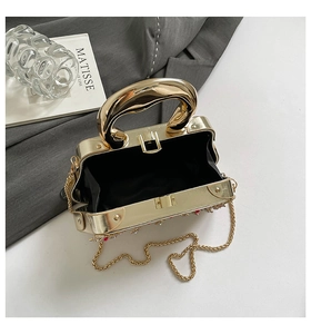 Détails d'un sac de soirée doré avec ornements en cristal et bandoulière à pompon en métal