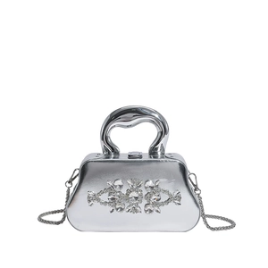 Gros plan du sac boîte argenté miroir avec fleurs en cristal et poignée métallique courbe