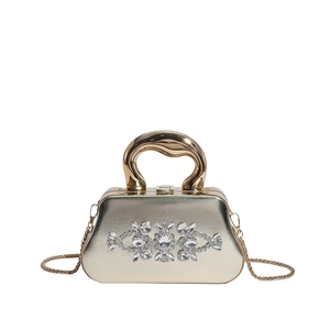 Vue détaillée de la pochette dorée ornée de strass en cristal et d'une poignée en métal