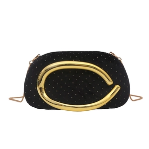 Détail de la pochette en velours noir avec poignée en C dorée et fine bandoulière chaîne