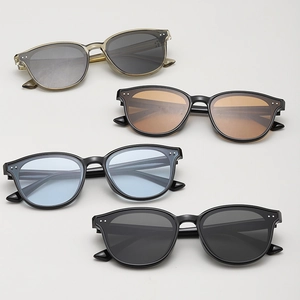 Flat lay of four classic round sunglasses with double dot rivets in various lens colors