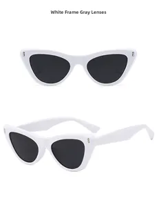 Detail view of white cat-eye sunglasses with grey lenses and metallic studs on the frame