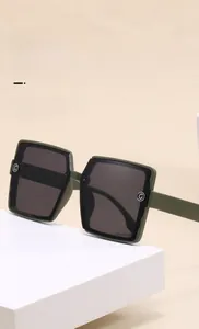Detail of olive green square sunglasses featuring silver metal G-shaped accents on the frames