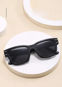 Top view of classic oversized black sunglasses with silver side bars on white podium