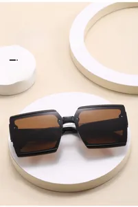 Close-up of stylish oversized square sunglasses with brown lenses on a white pedestal