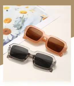 Détail de lunettes de soleil carrées oversize avec montures transparentes orange et grises