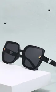 Detail view of black square oversized sunglasses with gold metal T-shaped hinge accents