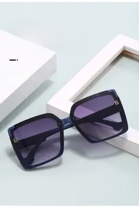 Dettaglio di occhiali da sole squadrati blu con lenti sfumate viola e logo B in metallo
