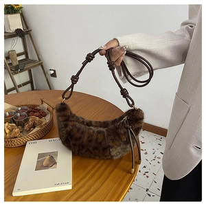 Detail of plush leopard print baguette bag with brown knotted leather shoulder strap