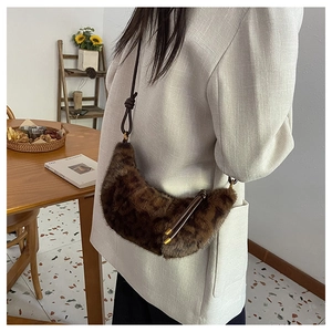 Detail of leopard print faux fur crescent bag with knotted strap in a cozy interior