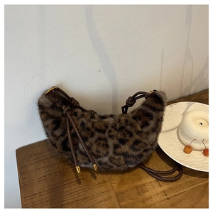 Detail of plush leopard print crescent bag with braided strap and gold metal tips
