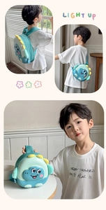 Detail of cute green dinosaur backpack showing plush yellow fins and 3D wing elements