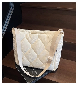 Detail of a beige quilted nylon shoulder bag with diamond pattern on a wooden step