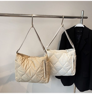 Detail of quilted rhombus pattern nylon shoulder bags in beige and white colors