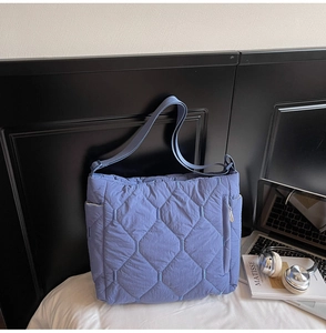 Blue quilted tote bag with diamond stitching shown next to laptop and headphones