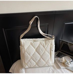 Close-up of quilted nylon crossbody bag featuring a side zipper pocket and adjustable strap