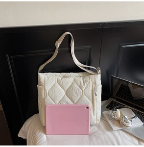 Detail of cream quilted nylon shoulder bag showing spacious interior and side zipper pocket
