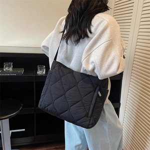Quilted black nylon puffer tote bag with silver zipper detail and wide shoulder strap