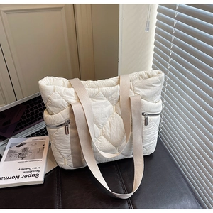 Detailed shot of quilted tote bag with diamond pattern and dual front zip pockets