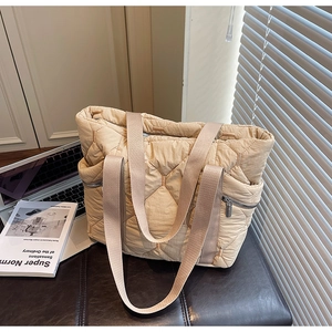 Detail of apricot quilted tote bag featuring hexagonal patterns and side zipper pocket