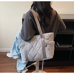 Detail of grey quilted down tote bag with hidden side zippers on a stylish model