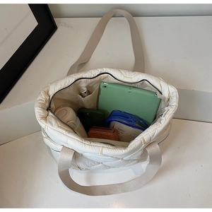 Detailed top view of a white quilted tote bag showing spacious interior with daily essentials