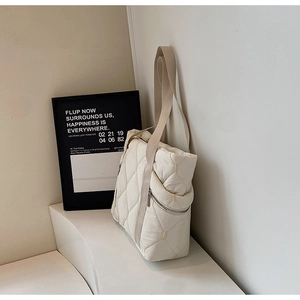 Detail of off-white quilted tote bag with side zipper pocket and nylon wide strap