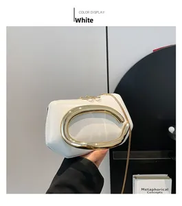 Detail of white mini square bag with golden C-handle and fine chain strap held by hand