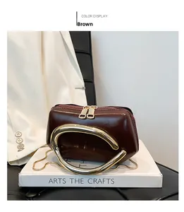 Detail of a mini brown leather bag featuring chunky gold metal handle and chain strap