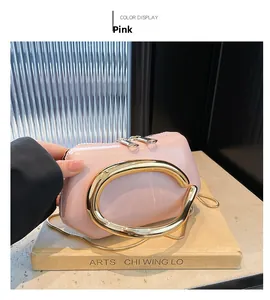 Pink patent leather handbag with gold metal handle and chain in art studio setting