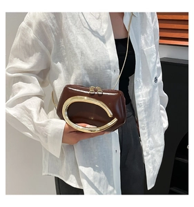 Close-up of vintage brown leather handbag with large gold C-shaped metal handle detail