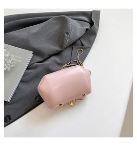 Macro shot of pink octagonal polyhedron handbag with thin gold metal chain on white desk