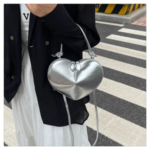 Detail of silver heart-shaped crossbody bag with metallic finish and adjustable shoulder strap