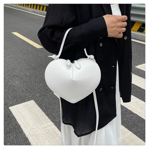 Street style shot of a white heart-shaped crossbody bag on a pedestrian crossing