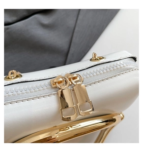 Detail of white faux leather bag showing gold dual zippers and metallic hardware